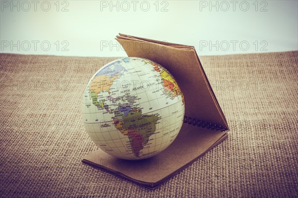 Globe with a notebook beside placed on canvas