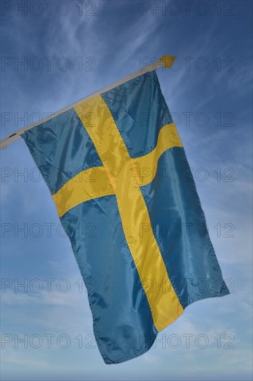 Flag of Sweden against a blue sky with veil clouds