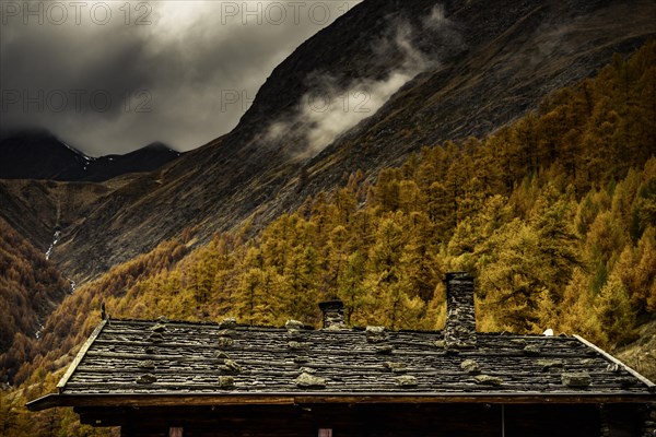 Alpine hut in autumnal mountain landscape with threatening cloudy sky