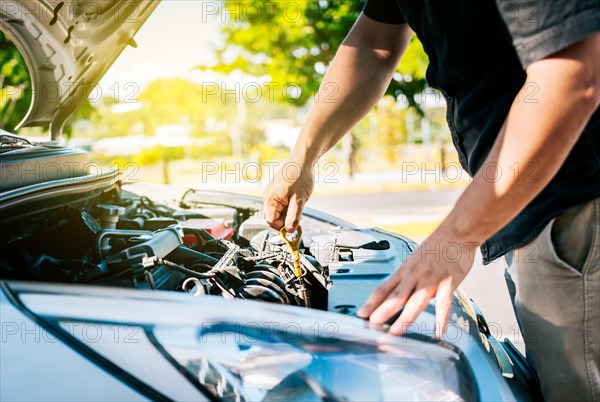 Driver hand inspecting car oil level