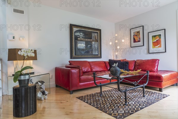 Red leather sectional sofa and black wrought iron with glass top coffee table in living room inside modern home