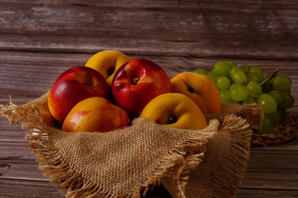 Group of fresh nectarines on a raffia cloth with a dark wood background