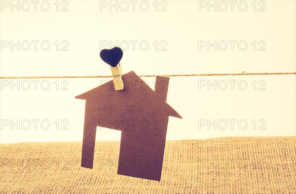 Little paper house attached to a string with a heart clip