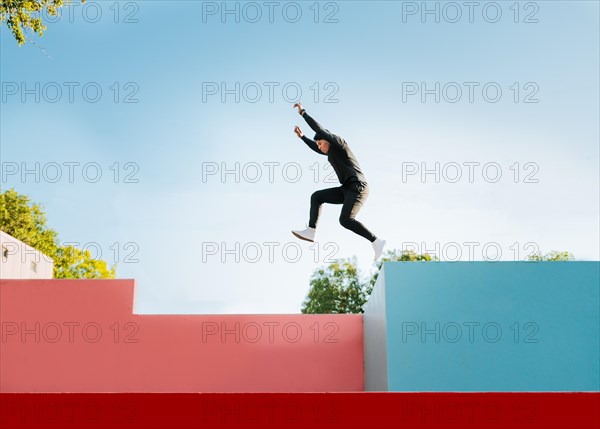 Guy doing parkour jumping colored walls. Guy doing jumping parkour at sunset. Side view of man doing parkour jumping walls