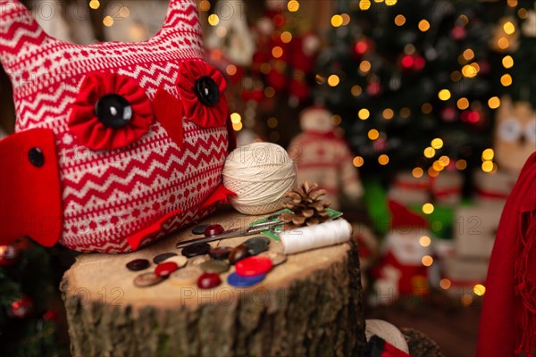 Grandmother sews a plush owl in Christmas arrangement. In studio