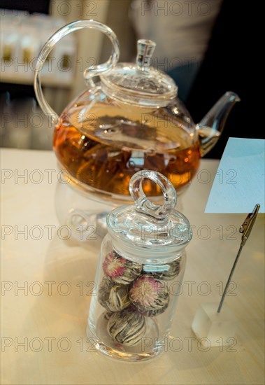 Herbal tea brewed in glass teapot and tea plant in a bottle