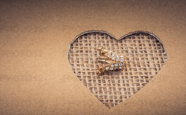 Crown seen through heart shape cut out of cardboard