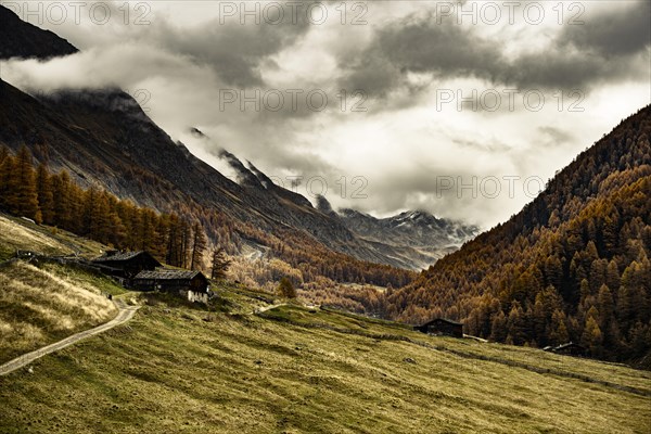 Alpine hut in autumnal mountain landscape with threatening cloudy sky