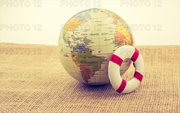 Life preserver beside a globe placed on canvas background