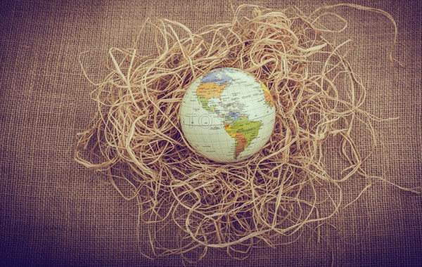 Globe placed on straw on canvas background