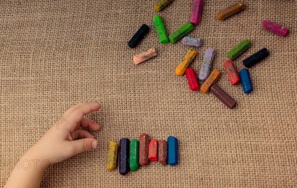 Toddlers hand putting crayons in line on canvas