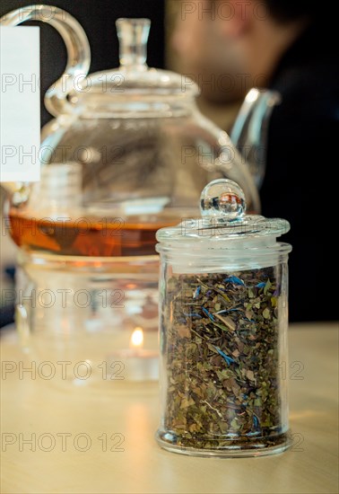 Herbal tea brewed in glass teapot and tea plant in a bottle