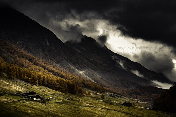 Alpine hut in autumnal mountain landscape with threatening cloudy sky