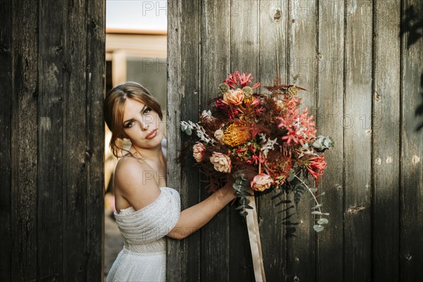 Beautiful bride with a bouquet with wooden door background as a background