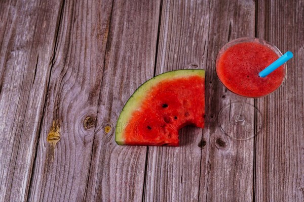 Cocktail glass with watermelon juice and slices of fresh watermelon on a wooden table