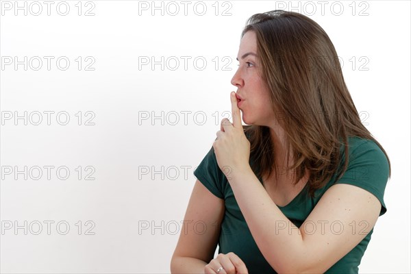 Close-up of a woman in profile with finger on mouth asking for silence on white background