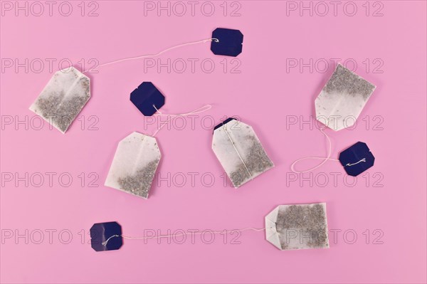 Tea bags with blank labels on pink background