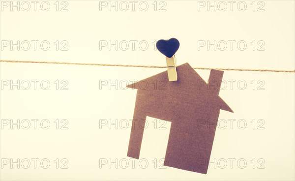 Little paper house attached to a string with a heart clip