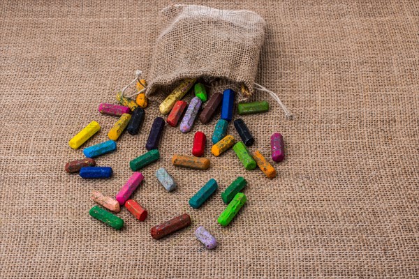 Crayons of various color out of a sack on a canvas