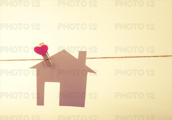 Little paper house attached to a string with a heart clip