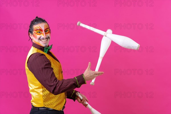 Clown with white facial makeup on a pink background