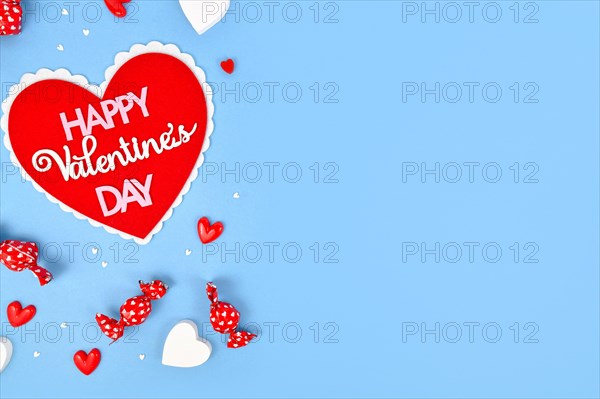 Valentines Day flat lay with heart with text Happy Valentines Day and heart ornaments on blue background with copy space