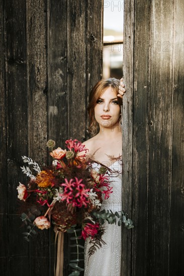 Beautiful bride with a bouquet with wooden door background as a background