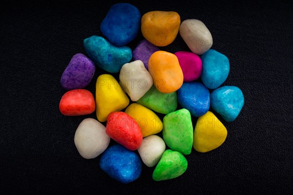 Pile of little colorful pebbles on black background