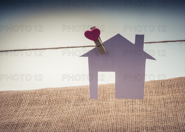 Little paper house attached to a string with a heart clip