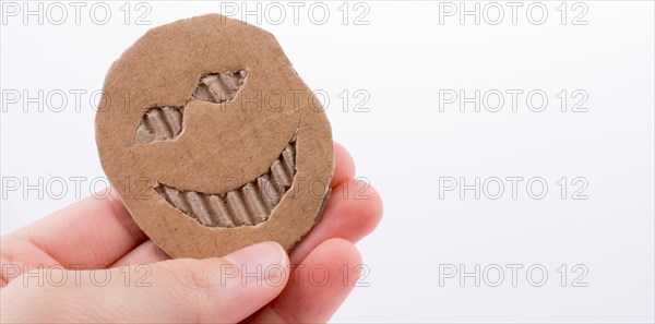 Hand holding a cardboard paper with smiley face