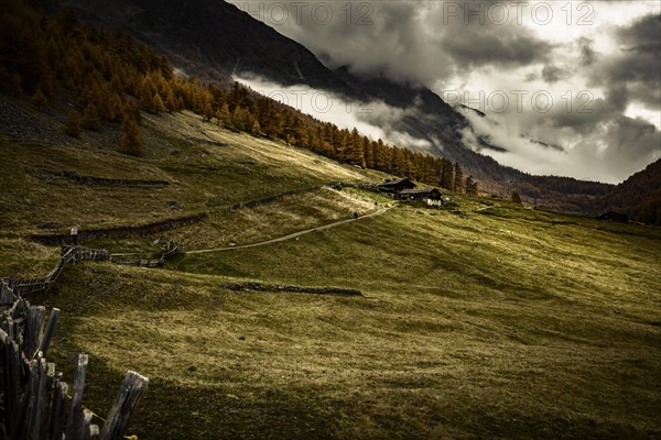 Alpine hut in autumnal mountain landscape with threatening cloudy sky