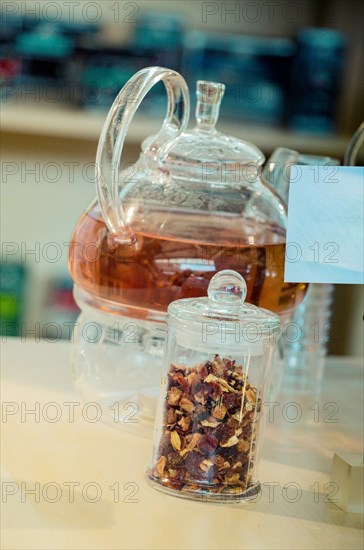 Herbal tea brewed in glass teapot and tea plant in a bottle