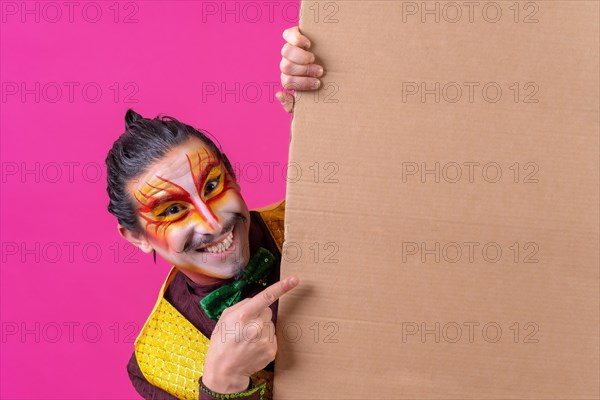 Clown with white facial makeup showing a sign on a pink background