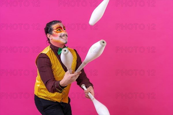 Clown with white facial makeup on a pink background