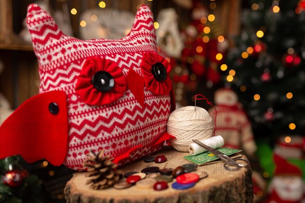 Grandmother sews a plush owl in Christmas arrangement. In studio