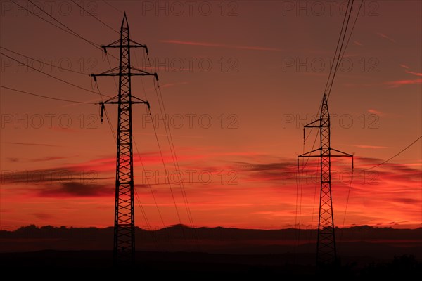 Silhouette of high voltage lines and transmission towers thru the Moravian field at sunrise