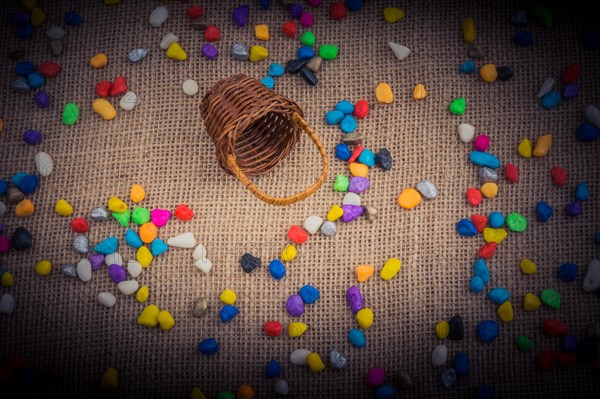 Basket and spilled pebbles on canvas background