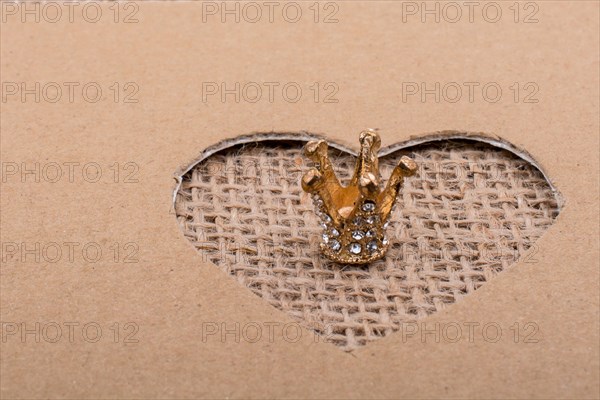 Crown seen through heart shape cut out of cardboard