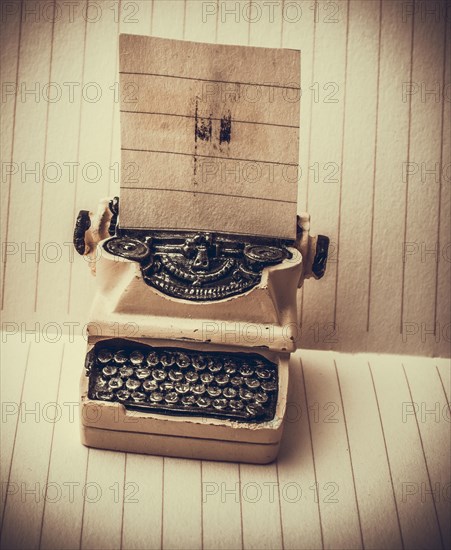 Retro syled tiny typewriter model on a paper background