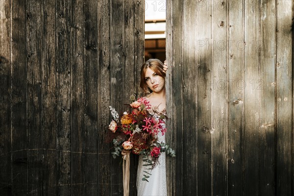 Beautiful bride with a bouquet with wooden door background as a background