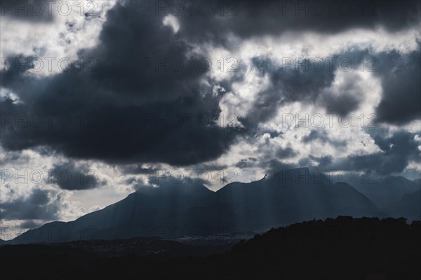 Dramatic sky with huge dark clouds over rugged mountain silhouettes in Spain