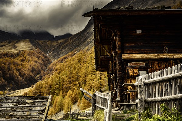 Alpine hut in autumnal mountain landscape with threatening cloudy sky