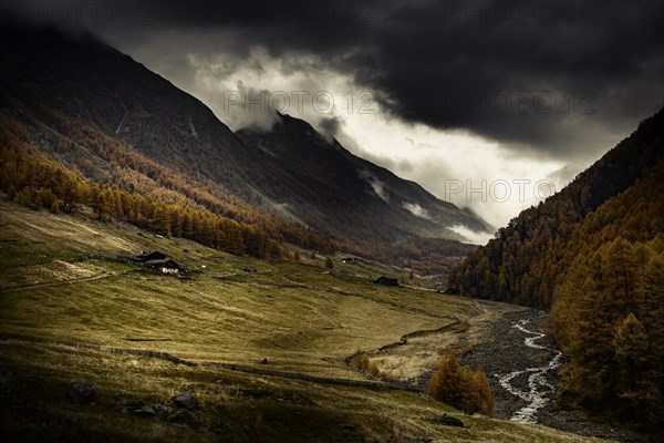 Alpine hut in autumnal mountain landscape with threatening cloudy sky