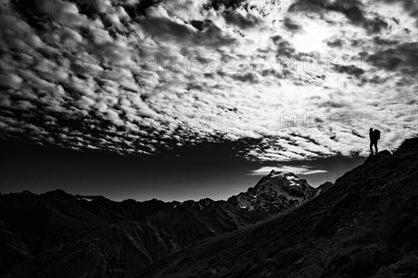 Mountaineer in backlight with cloudy sky in front of Ortler summit massif