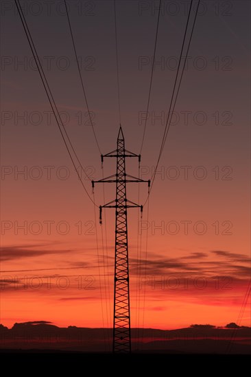 Silhouette of high voltage lines and transmission towers thru the Moravian field at sunrise