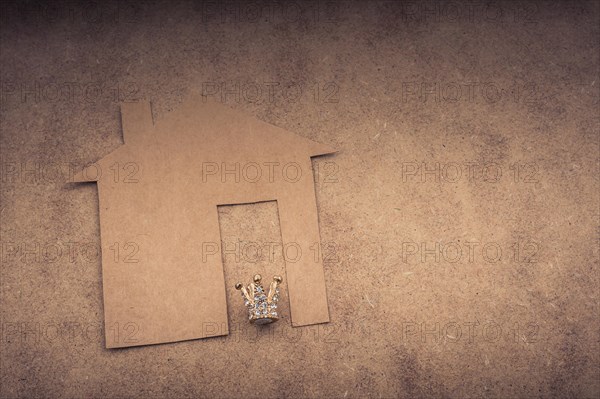 Litle model crown and paper house on a brown background