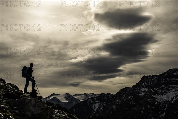 Climbers on rocks in backlight with cloudy sky in the background South Tyrolean mountains