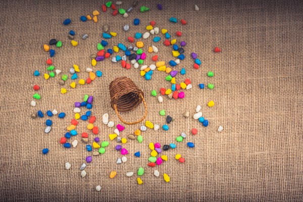 Basket and spilled pebbles on canvas background