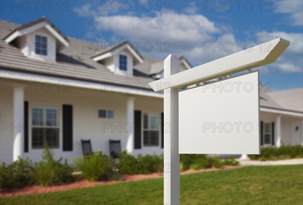 Blank real estate sign in front of new house