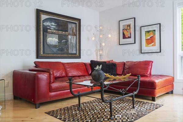 Red leather sectional sofa and black wrought iron with glass top coffee table in living room inside modern home